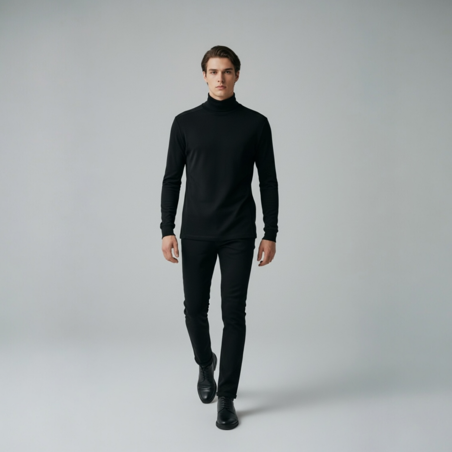 Mann in schwarzem Rollkragenpullover und Hose von DMANERA Atelier auf neutralem Hintergrund