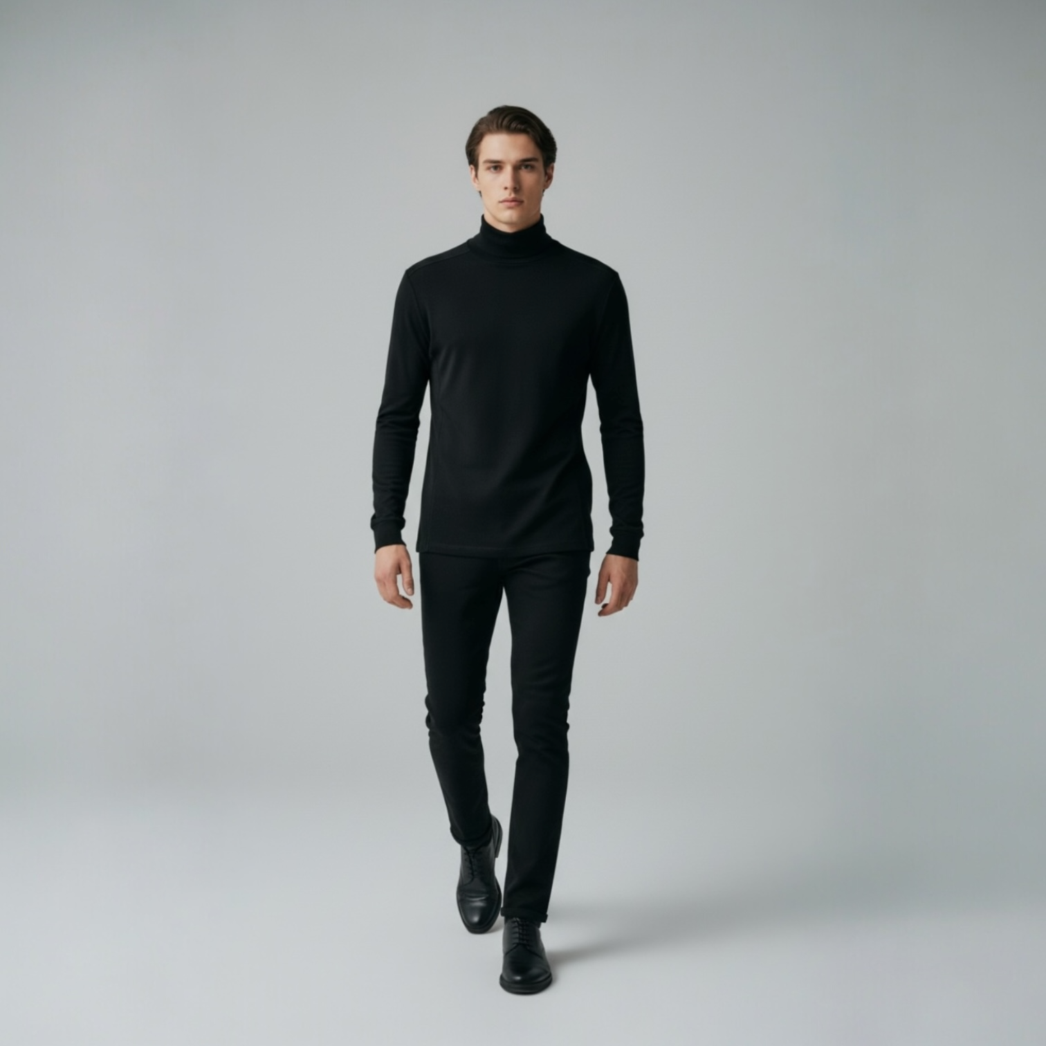 Mann in schwarzem Rollkragenpullover und Hose von DMANERA Atelier auf neutralem Hintergrund